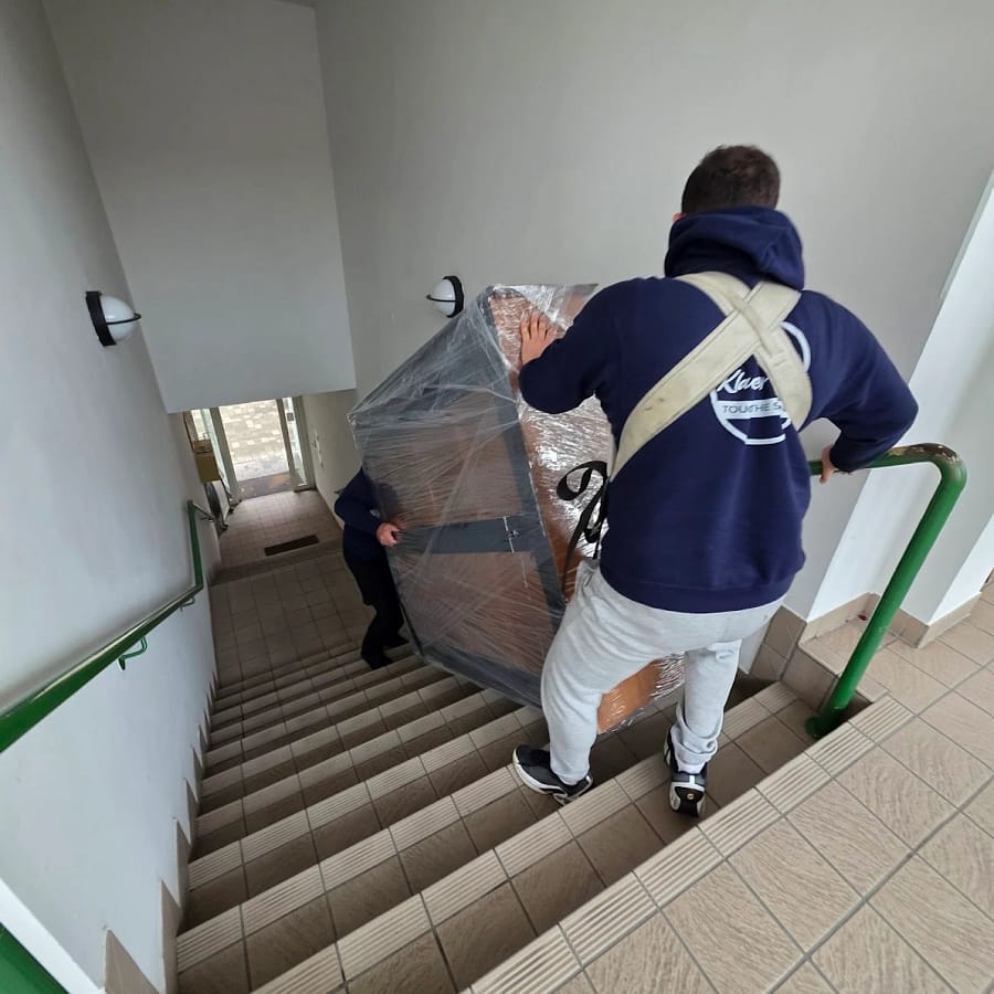 Verpacktes Klavier wird über die Treppe getragen