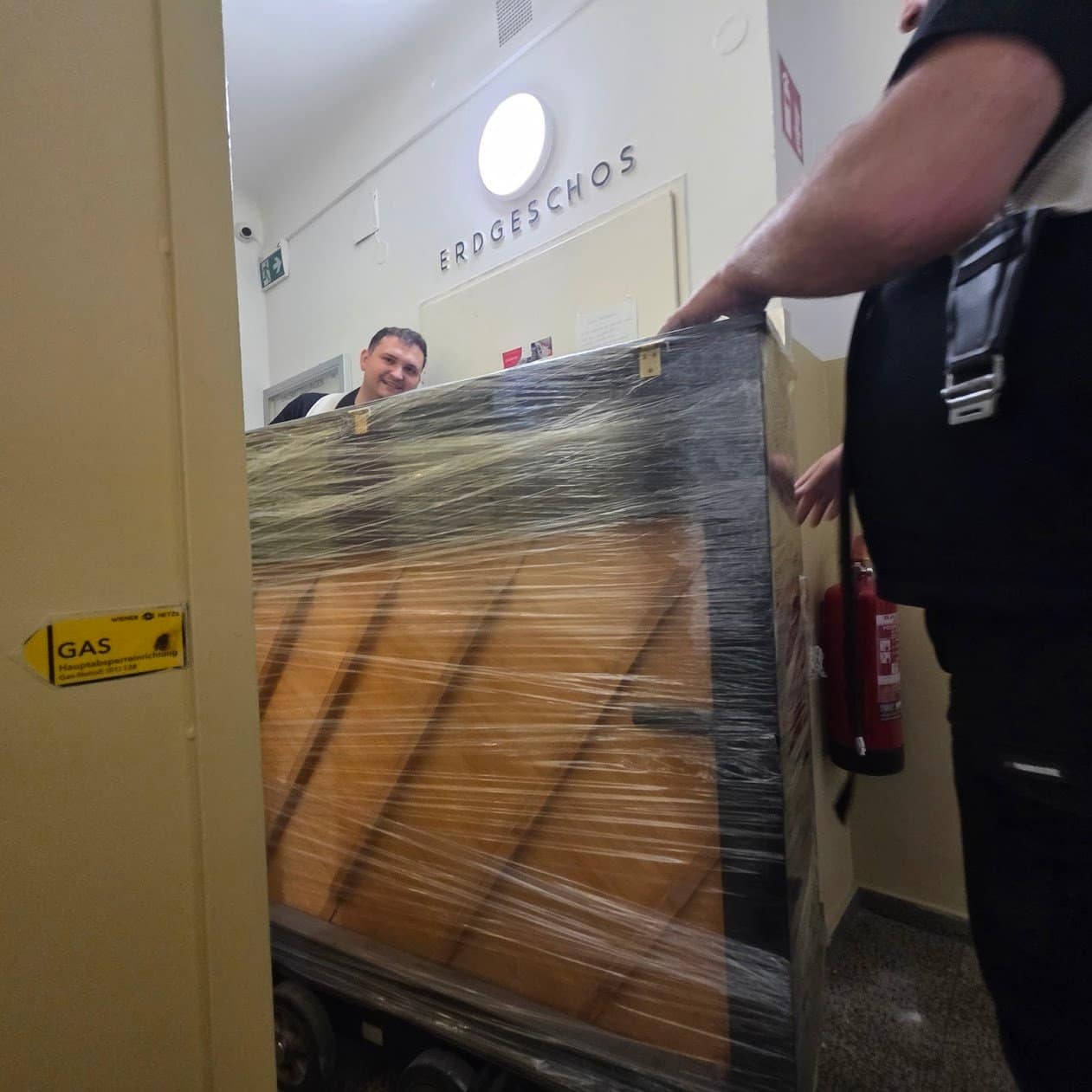 Piano transport Gänserndorf: a wrapped piano waiting in the entrance hall before the drive