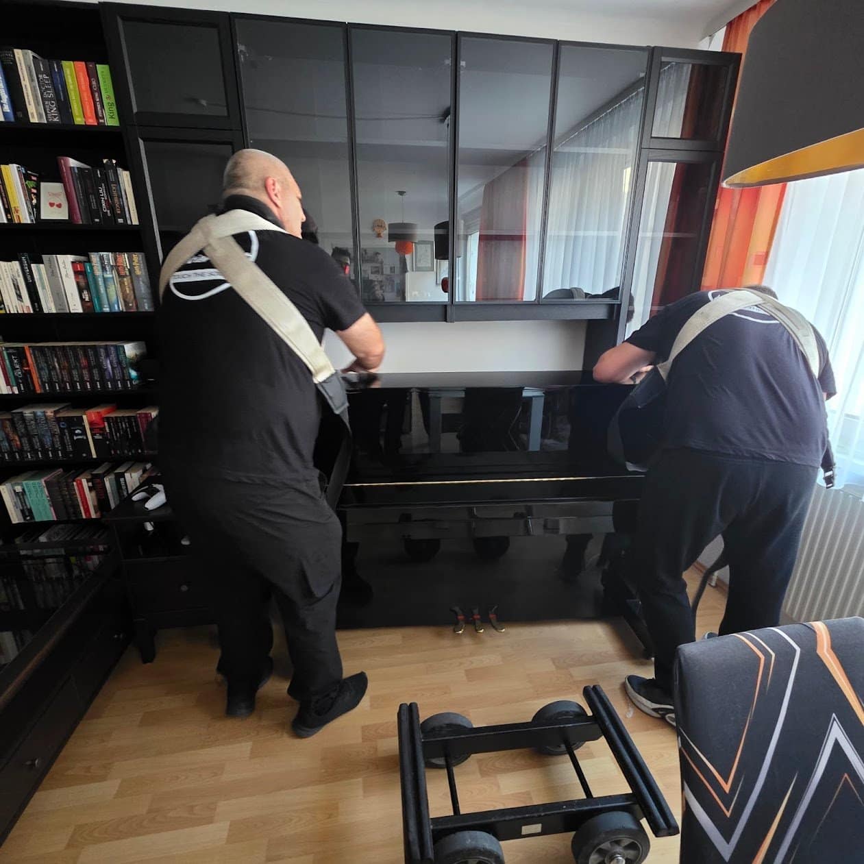 Piano transport Korneuburg: two carriers lift a piano with straps inside the flat