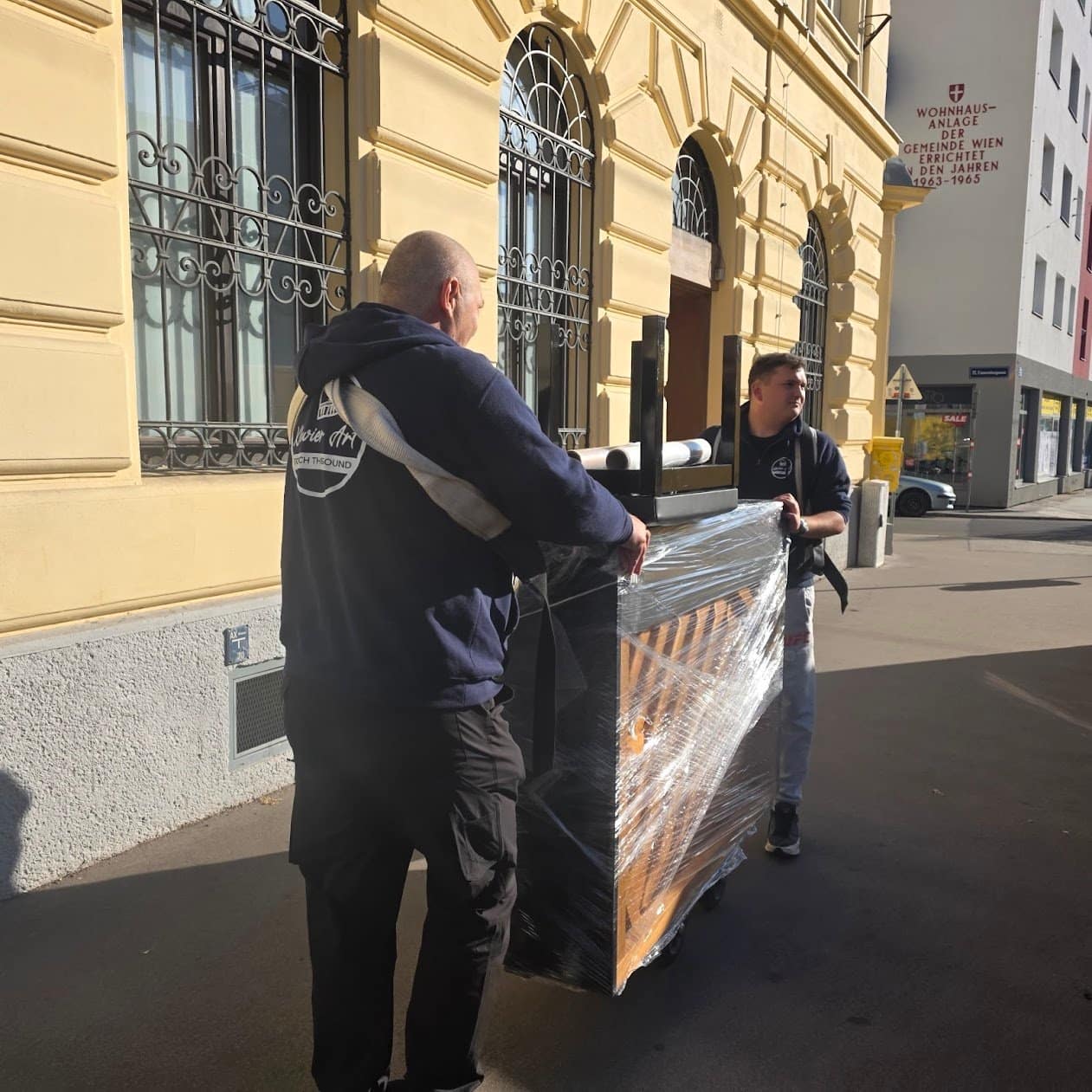 Piano transport Bruck an der Leitha: a carrier with the wrapped piano in front of an old town facade
