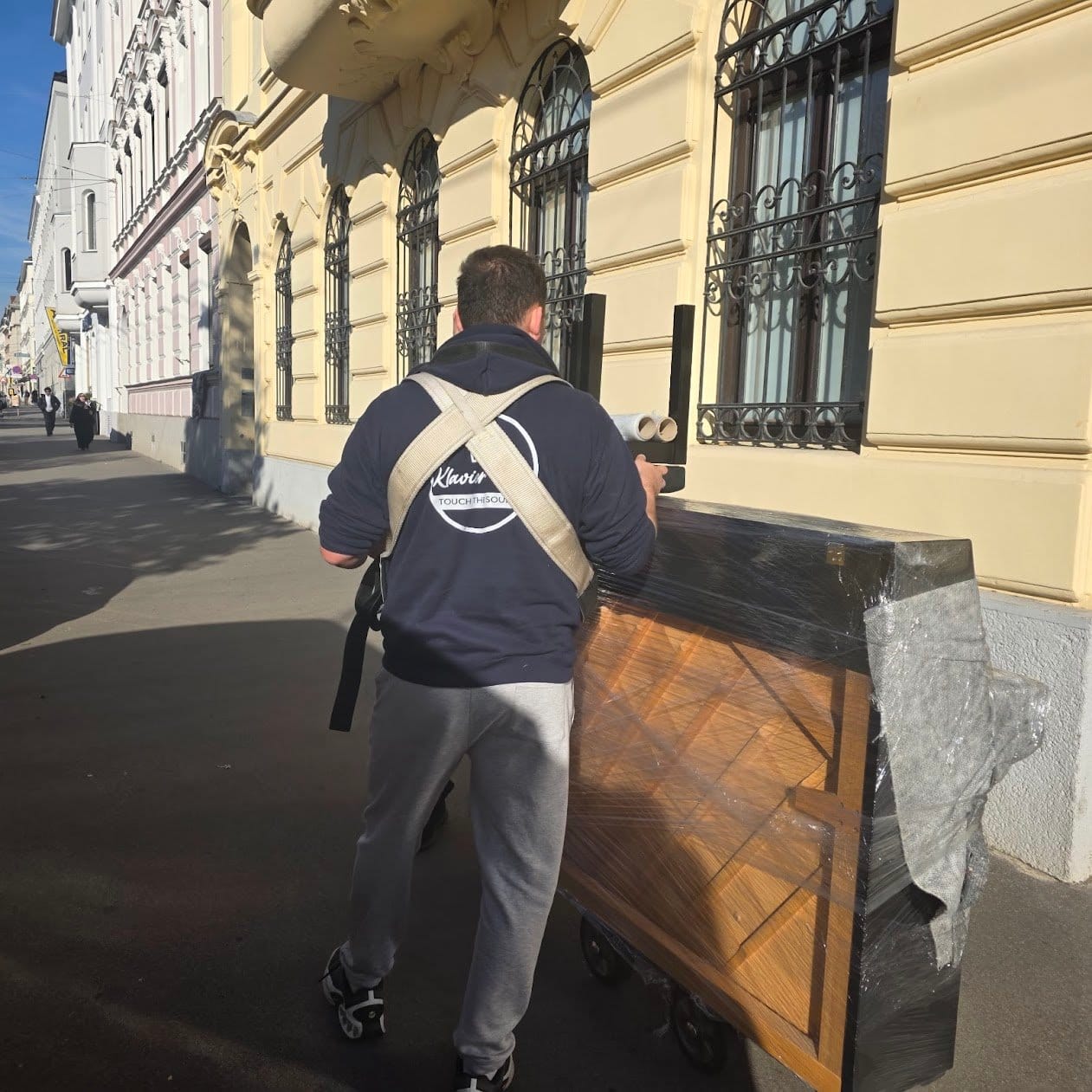 Piano transport Schwechat: a carrier pulls the wrapped piano along the street to the vehicle