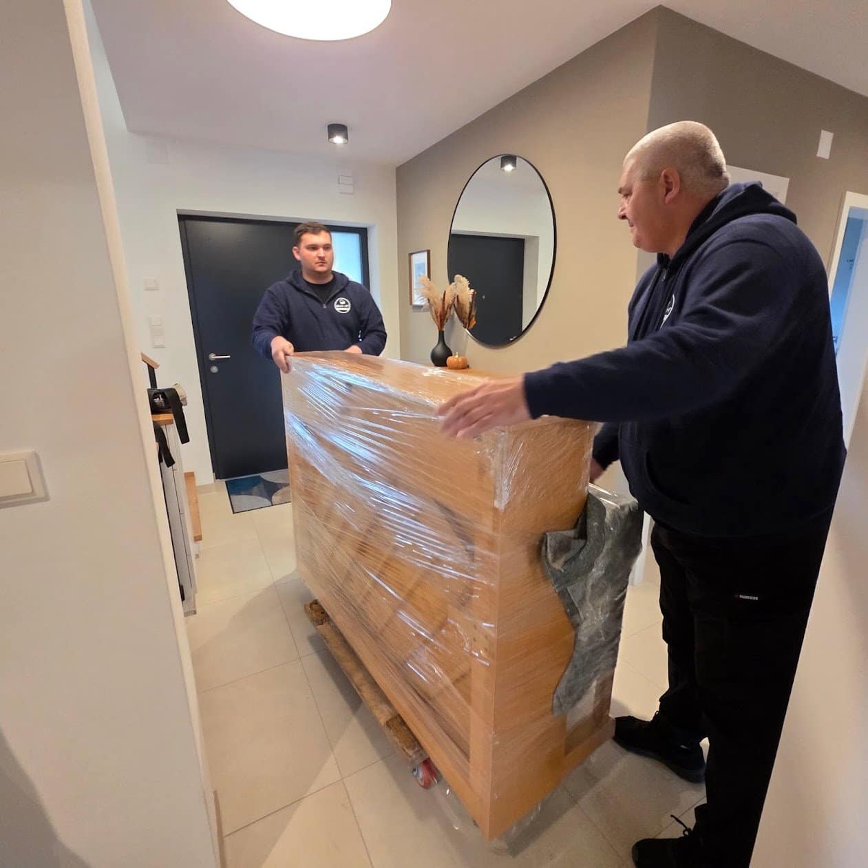 Klaviertransport Stockerau: verpacktes Klavier auf dem Rollwagen im Hauseingang