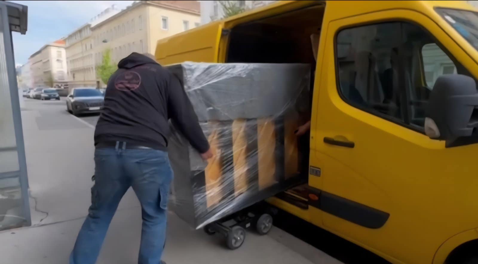 Mitarbeiter von MK Klavier Art verlädt ein verpacktes Klavier in den Transporter