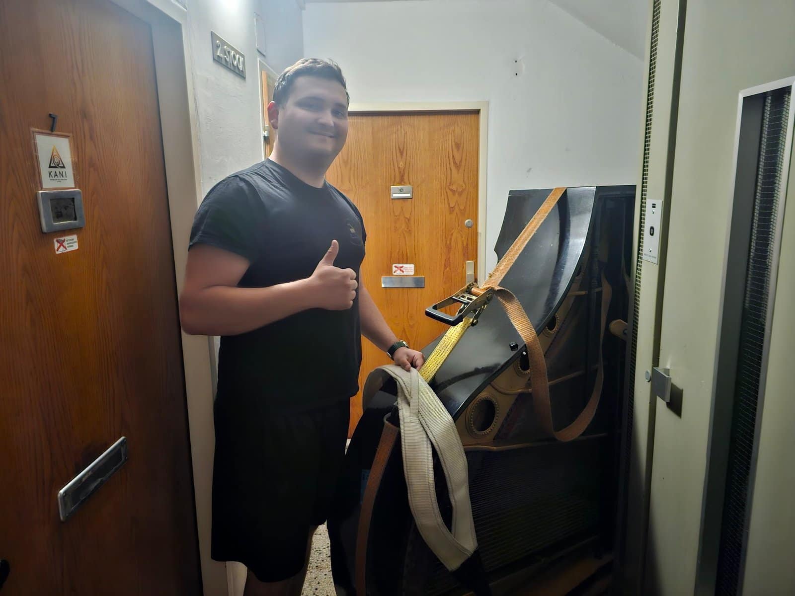 Piano transport Mödling: a carrier with the strap at the flat door, the piano ready to leave