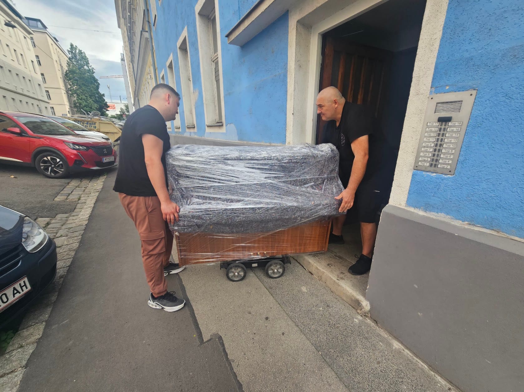 Klaviertransport Bruck an der Leitha: verpacktes Klavier wird durch die Haustür auf den Gehsteig gebracht