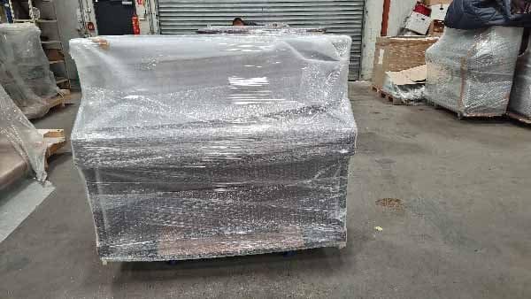 An upright piano being packed and strapped for transport abroad
