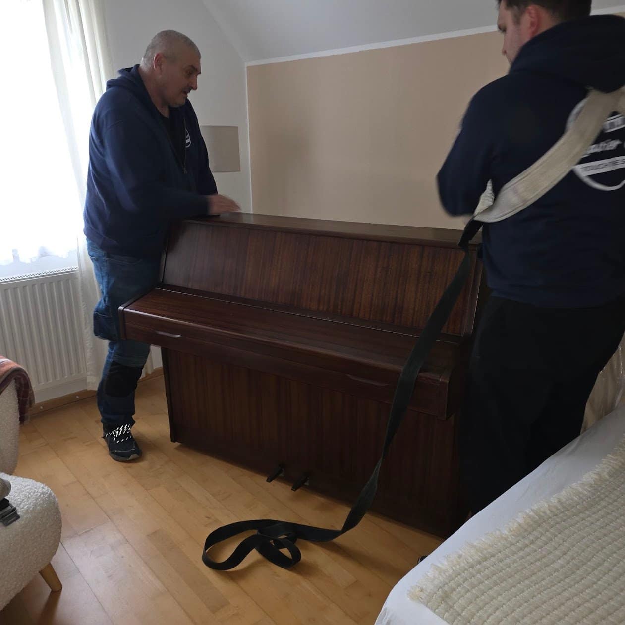 Zwei Männer unseres Teams tragen ein Klavier in einer hellen Wohnung